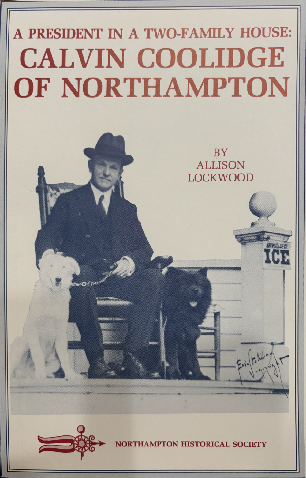 Calvin Coolidge sits in a chair next to two dogs on the cover of the book, "Presindent in a Two-Family House"